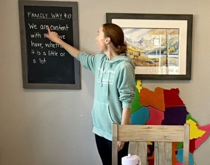 mom pointing to family way written on chalkboard in kitchen
